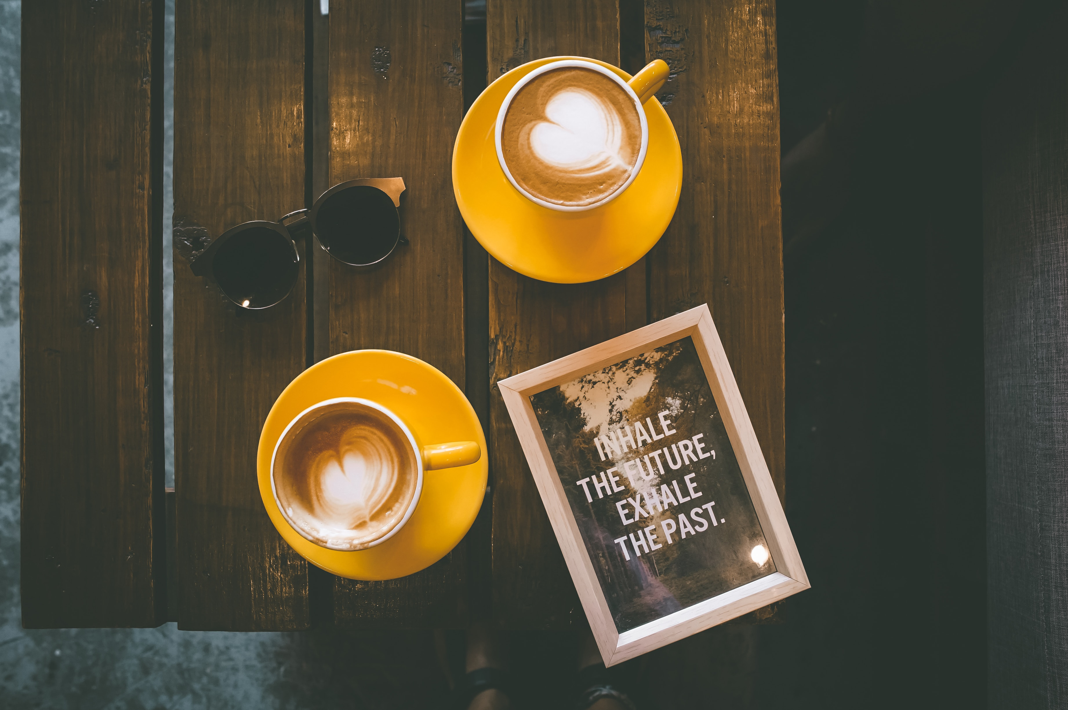 A photo from Cebu City, Philippines, showing two mugs containing cappuccinos on a table alongside a picture frame containing a quote with these words all in capital letters: "INHALE THE FUTURE, EXHALE THE PAST"