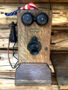A close up image of an old wooden telephone with metal ringing bells, a speaker, and a receiver