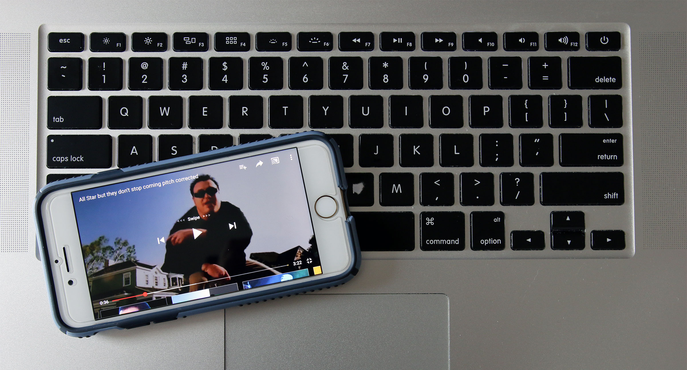 A computer keyboard with an iPhone on top of it streaming a music video