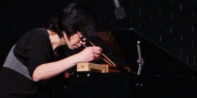 Ju-Ping Song at a toy piano with chopsticks