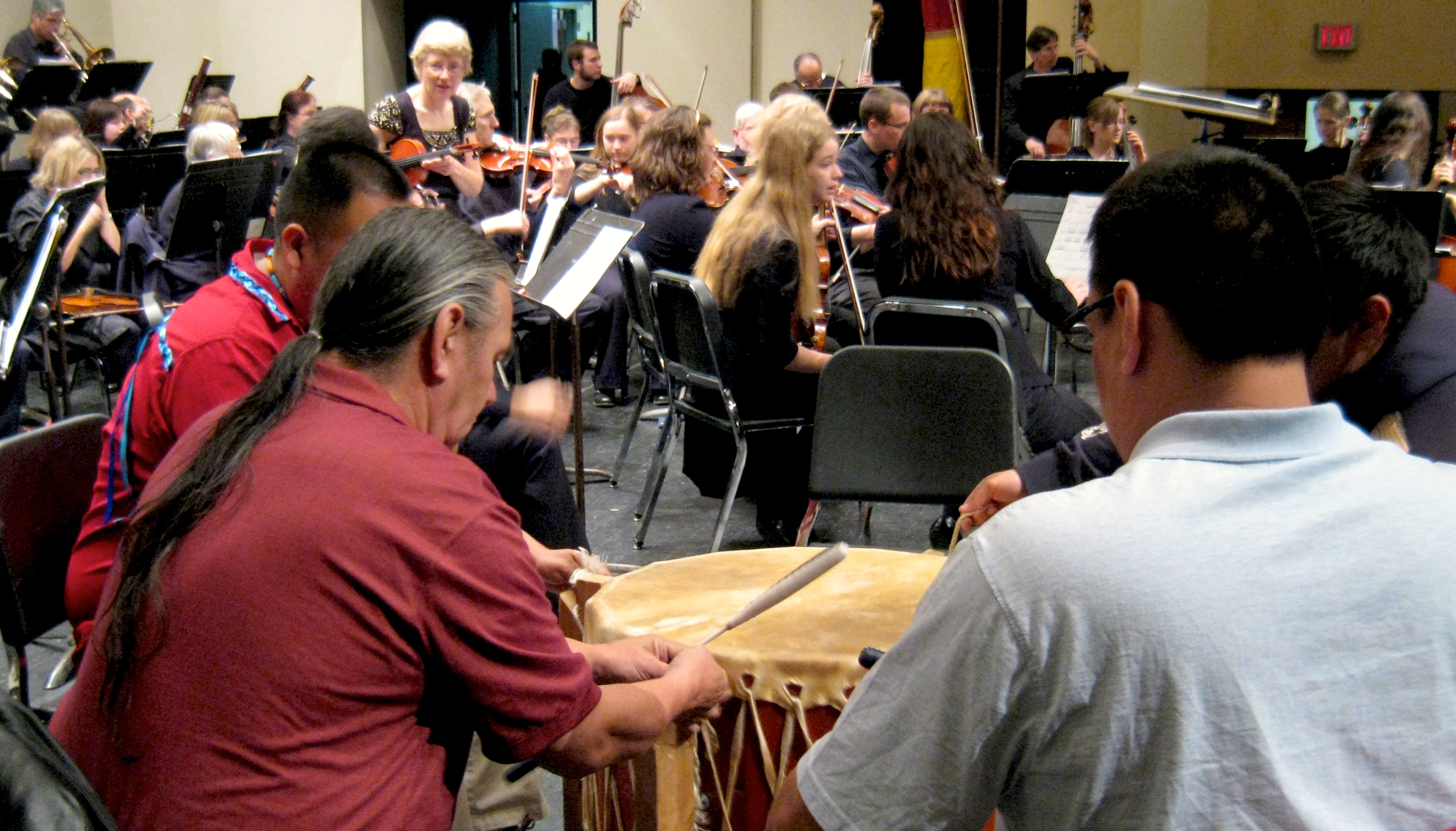 Two Native American drummers rehearsing with the members of a symphony orchestra