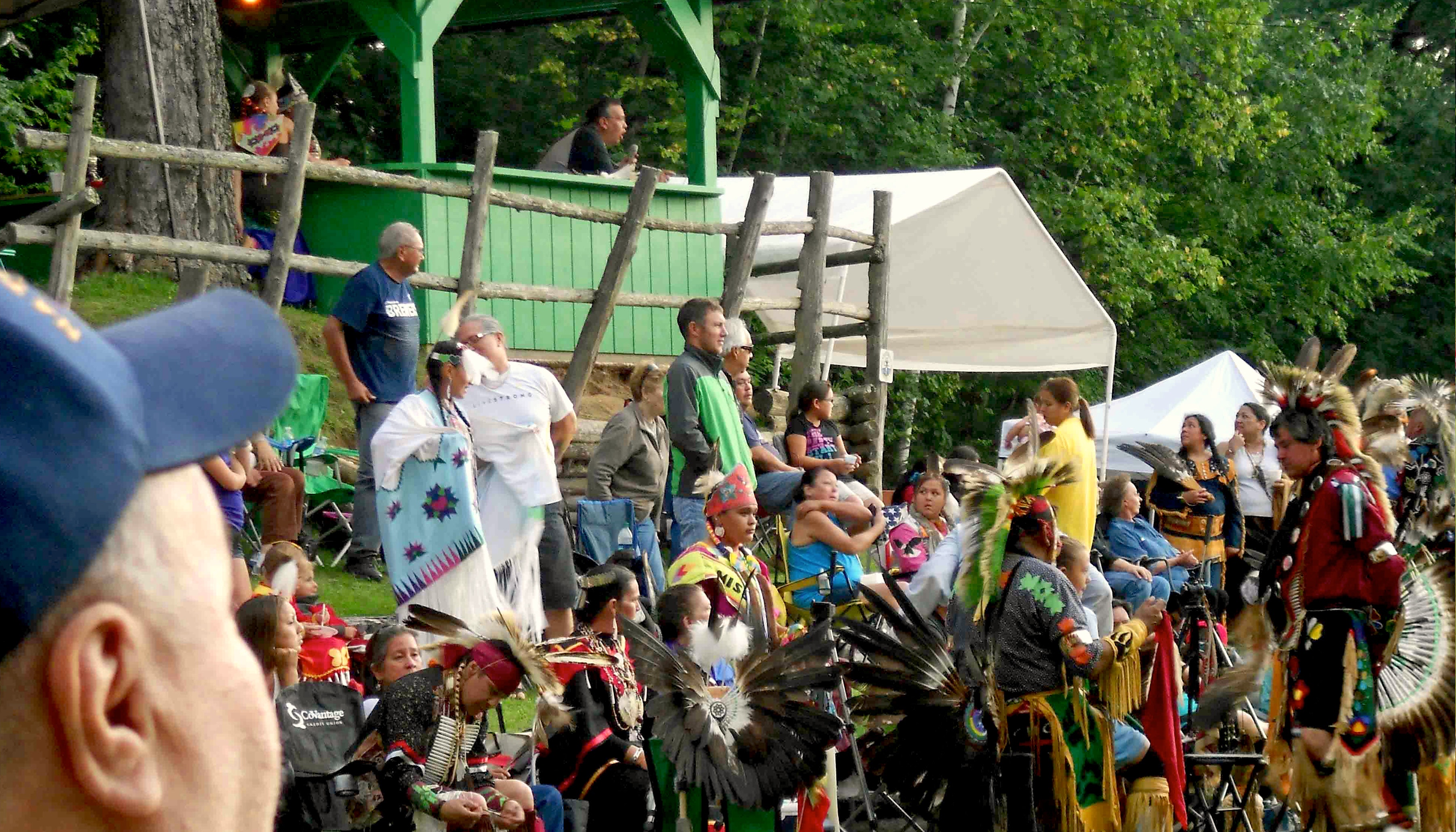 Various people assembled outdoors at a Mohican Nation powwow.