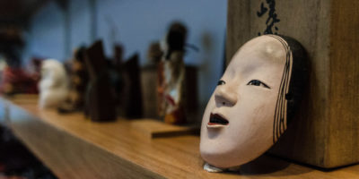 A Japanese face mask on a shelf with other objects that are out of focus.