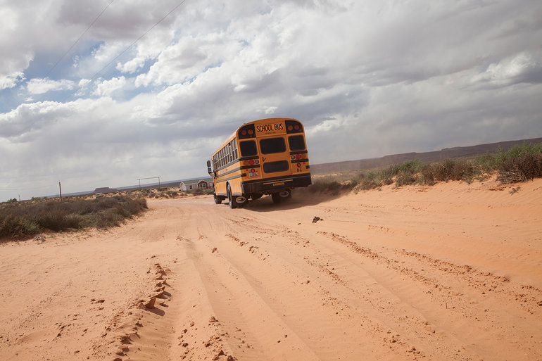 A school bus on an otherwise empty dirt road.