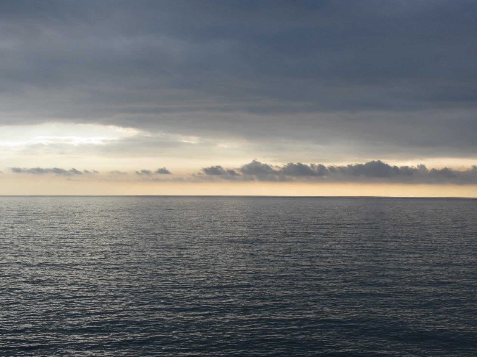 A photo of a large body of water meeting a cloudy sky at the horizon.