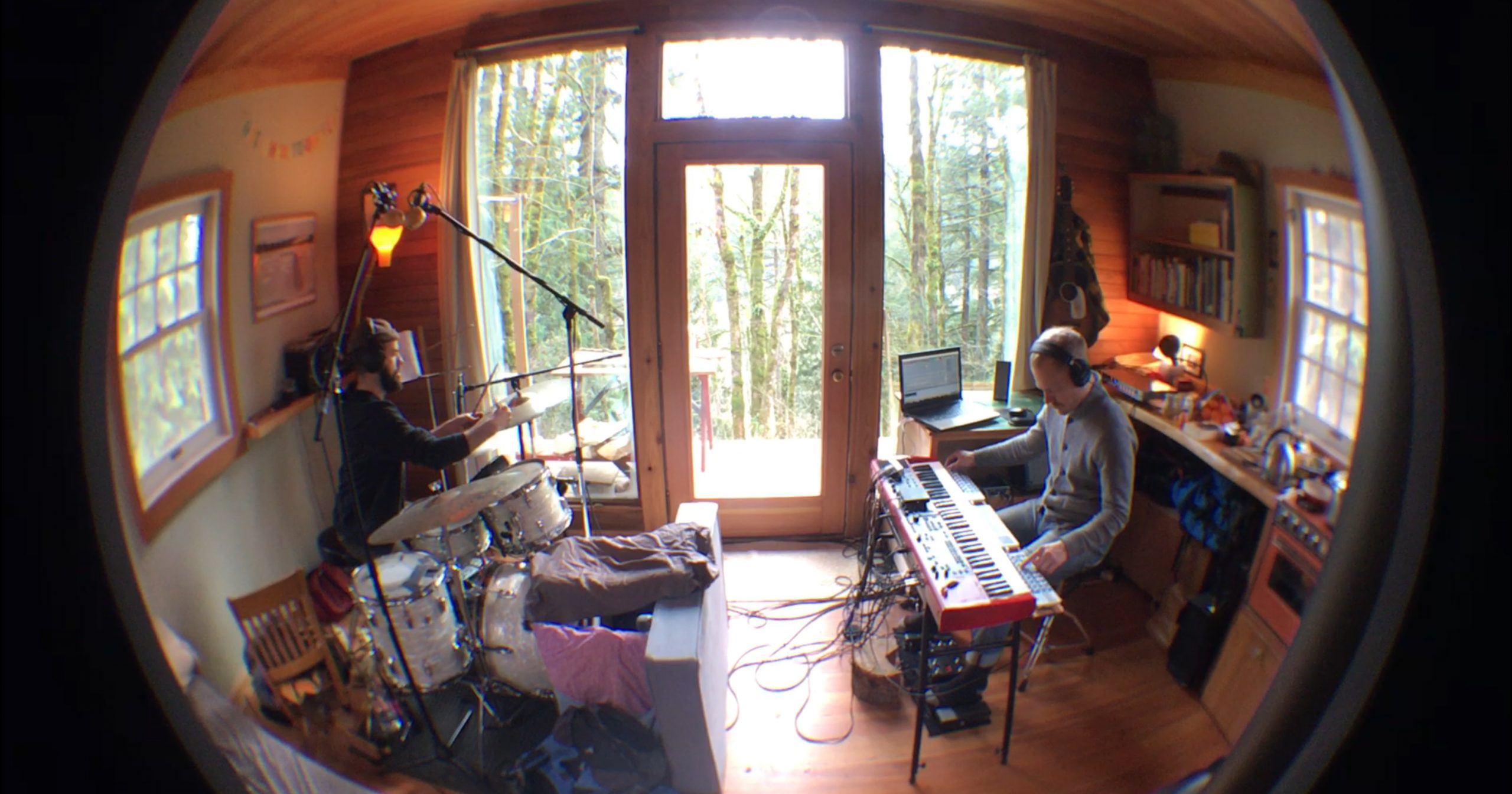 A fisheye lens photo of Methods Body (John Niekrasz on drumset and Luke Wyland on electric keyboard) performing in a cabin.
