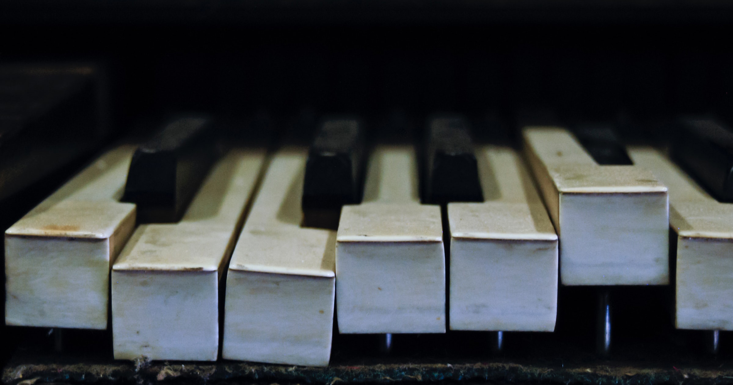 A close up of a piano keyboard with broken/warped keys going in various directions.