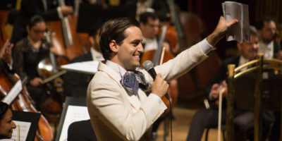 A Latinx man waving from the orchestra stage