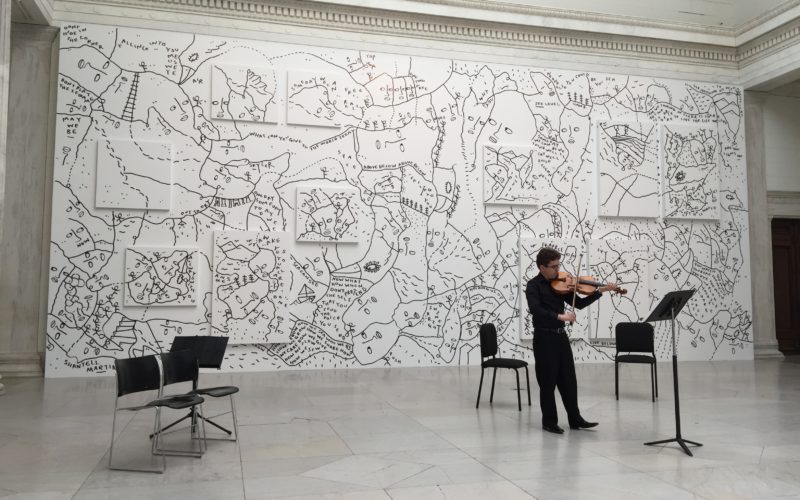 A string player performs in an art exhibit