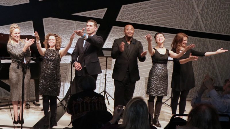 Six performers receive applause on a stage.