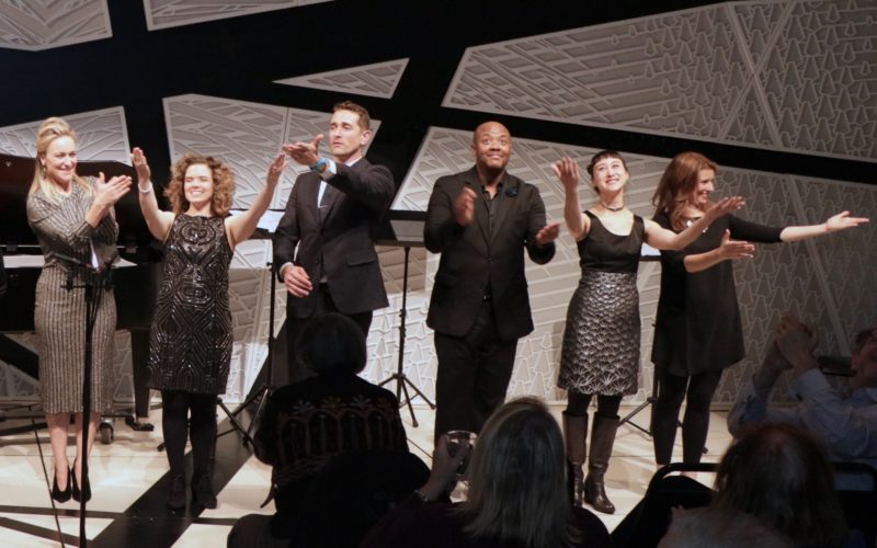 Six performers receive applause on a stage.