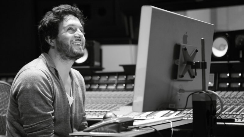 black and white photo of a Latinx man at a computer, smiling
