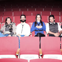 Ensemble sitting in red theater chairs