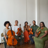 A string quartet and executive director posing in a clear, white space