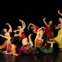 Dancers bend and pose amidst a dark background
