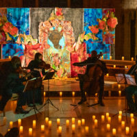 The Harlem Chamber Players; a string quartet performing in an intimate space including a shrine and candles