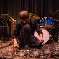 Tim Daisy performing on the floor with glass bowls