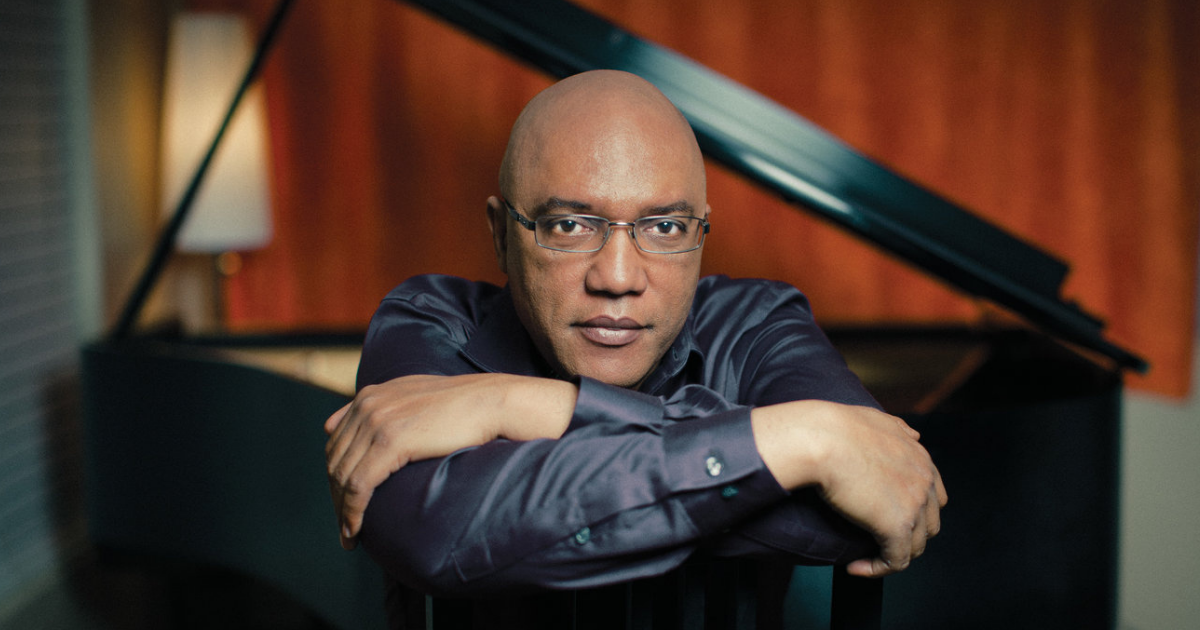 Billy Childs sitting in front of a grand piano.