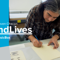 Banner for the Raven Chacon episode of SoundLives featuring a photo of Raven writing music on a piece of score paper.