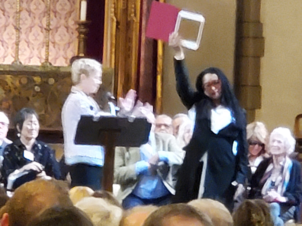 Pamela Z waves her induction certificate as Augusta Read Thomas and others applaud her.