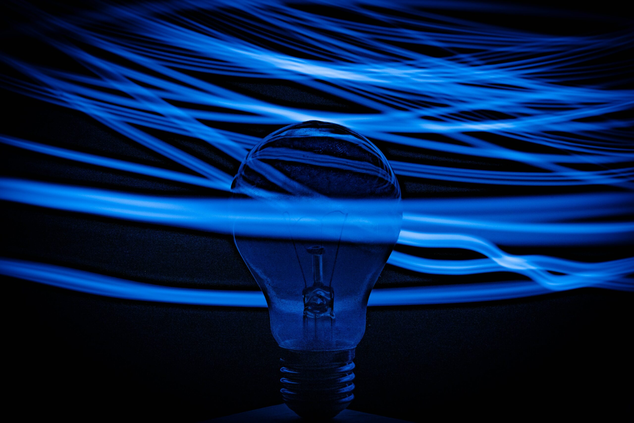 Image of a light bulb in the middle of a cascade of electric waves by Nejc Soklič (via Unsplash)