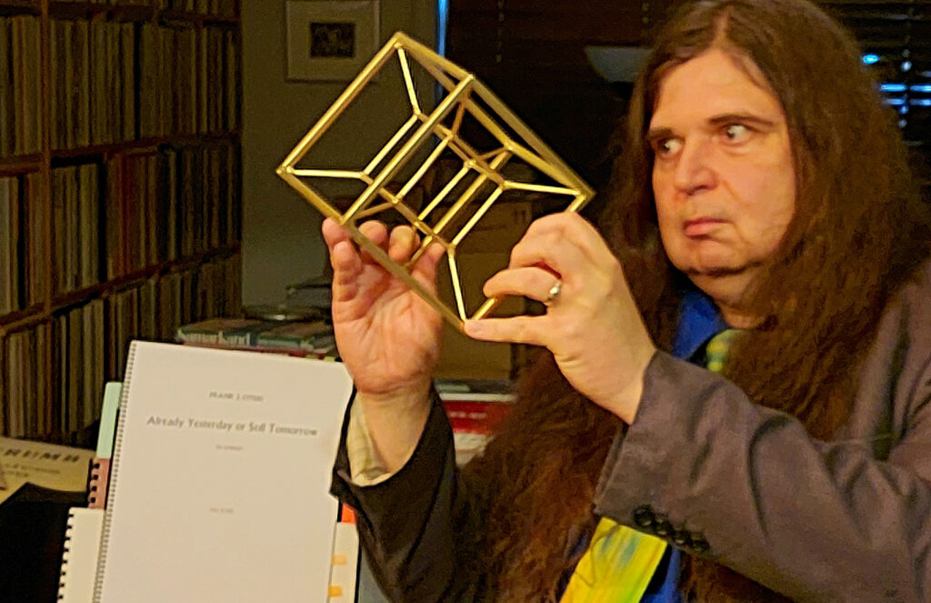 Oteri holding a three-dimensional simulacrum of a tesseract.